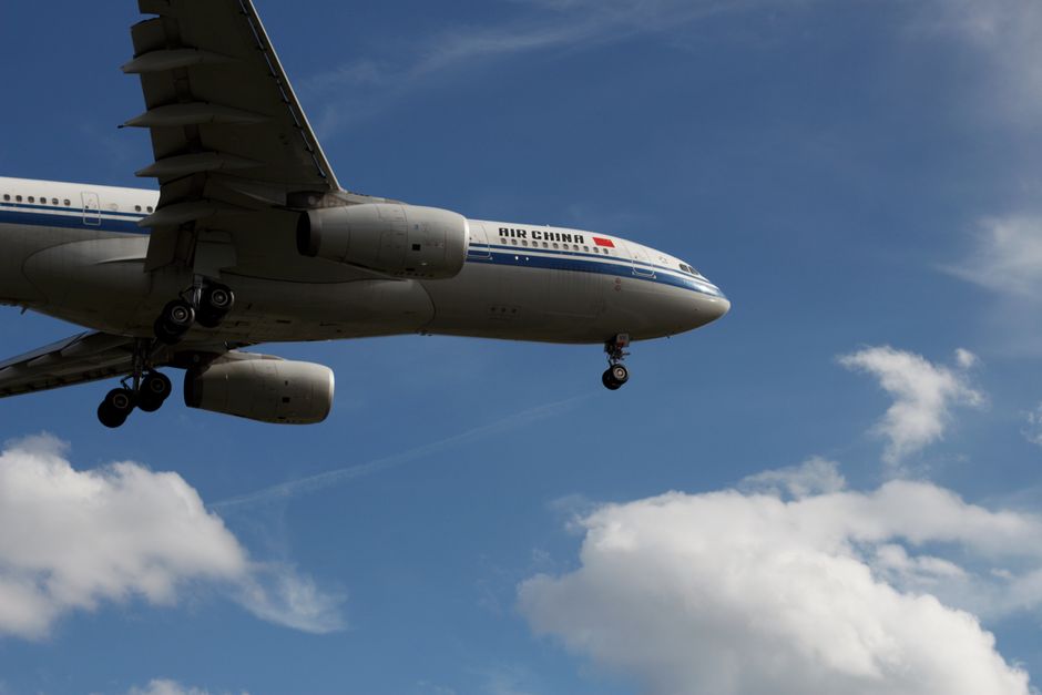 Air China airplane flying under a blue sky with clouds, in Frankfurt.