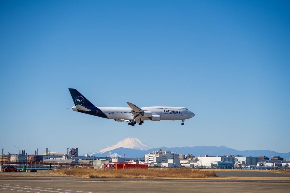 A Lufthansa Boeing 747 landing at an airport with Mount Fuji visible in the background on a clear day.