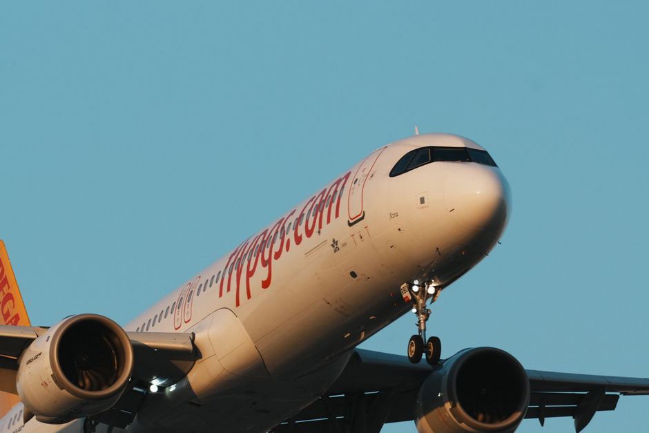 Passenger aircraft approaching for landing over clear blue sky at Istanbul airport.