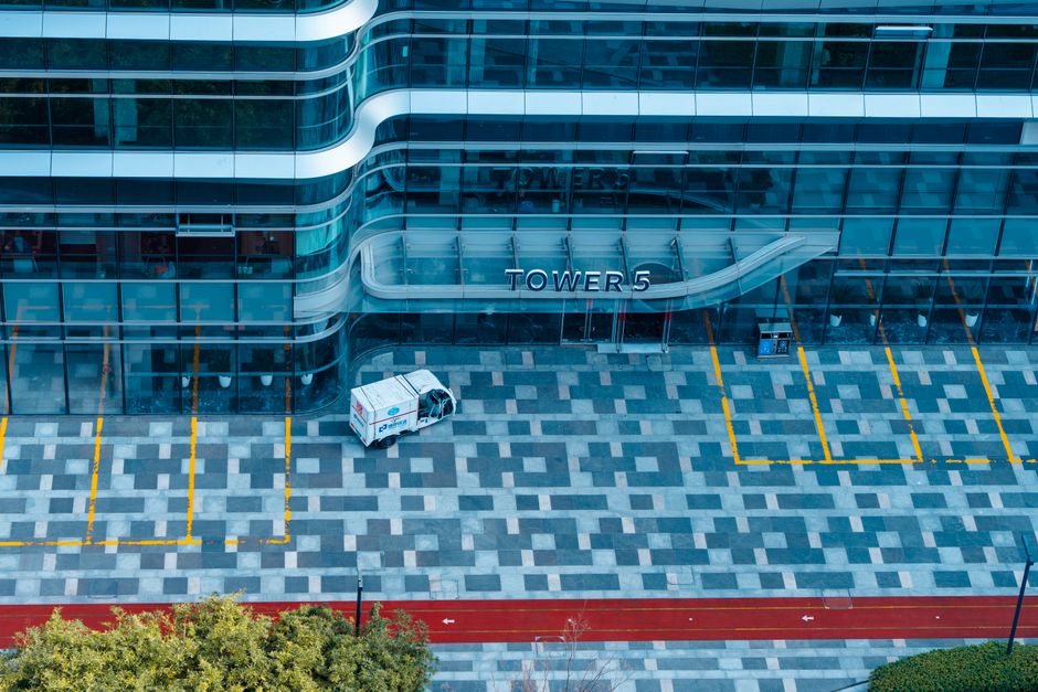 Aerial view of Tower 5's sleek glass facade in Hangzhou, China, featuring a geometric parking lot.