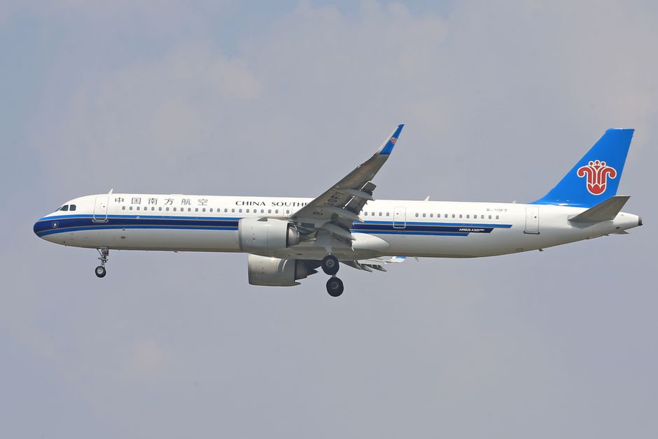 China Southern Airlines Airbus captured in mid-flight with landing gear deployed against a clear sky.