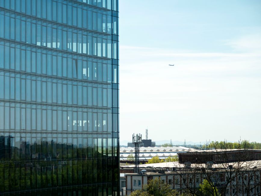 View of a modern glass building with a cityscape and airplane in the distance in Wrocław, Poland.